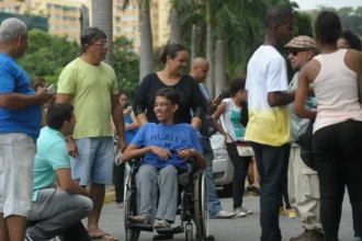 um grupo de pessoas em pé ao redor de um homem em uma cadeira de rodas