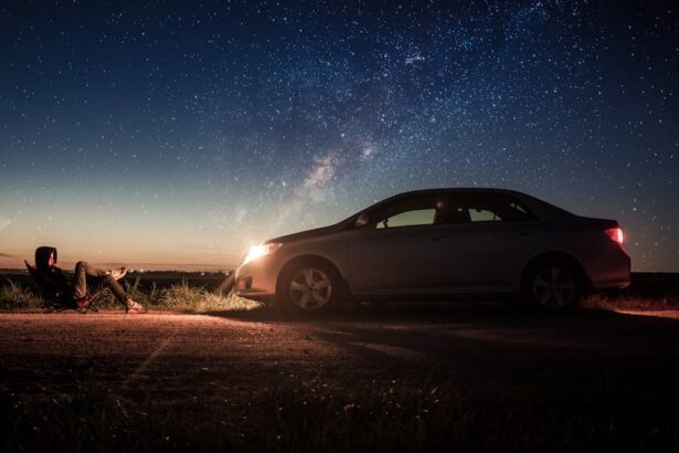 Um carro parado com os farois iluminando um homem sentado.