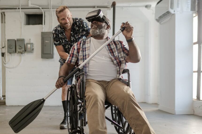 Homem em cadeira de rodas remando usando óculos de realidade virtual, acompanhado por outro homem.