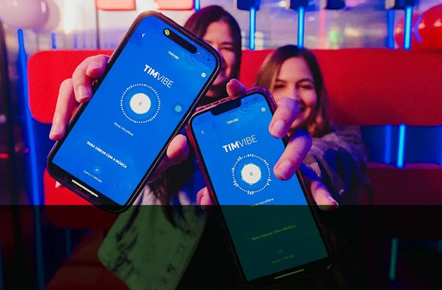 Duas mulheres sorrindo seguram celulares com o aplicativo TIM Vibe aberto, em um ambiente colorido com luzes neon. As telas dos aparelhos exibem a frase “Para vibrar com a música”