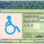 Imagem de uma Carteira Nacional de Habilitação (CNH) brasileira adaptada para pessoa com deficiência. No lado esquerdo da CNH, há um símbolo azul de acessibilidade.