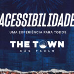 Cartaz do festival The Town São Paulo com fundo azul, fogos de artifício e prédios ilustrados. Em destaque, a frase: 'Acessibilidade – Uma experiência para todos. THE TOWN São Paulo'.