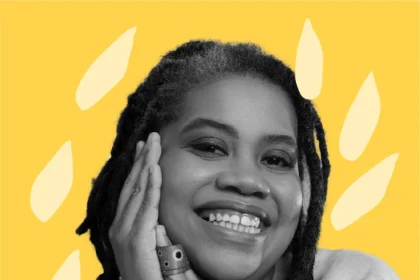 Luciana Viegas, sorrindo e apoiando o rosto nas mãos. Ela veste uma blusa clara e está em frente a um fundo amarelo com formas orgânicas decorativas.