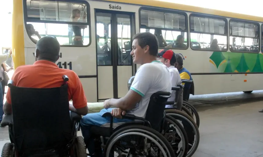 Grupo de homens cadeirantes aguardando em frente a um ônibus de transporte público.