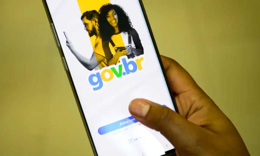 Pessoa segurando um celular que exibe a tela inicial do aplicativo Gov.br, com o logotipo colorido e a opção de login