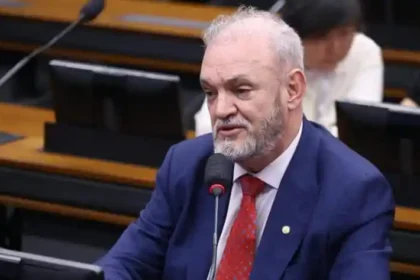 Homem de terno falando ao microfone durante audiência em comissão parlamentar.