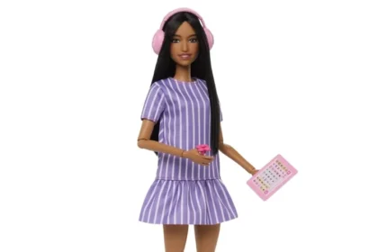 Boneca Barbie negra usando vestido lilás listrado, fones de ouvido rosa e segurando um tablet.