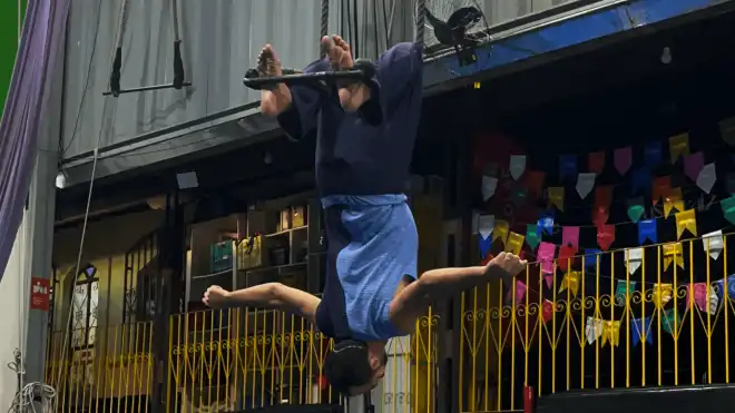 Pessoa realiza uma apresentação de tecido acrobático de cabeça para baixo em um espaço cultural. A imagem destaca a participação de artistas com deficiência nas artes circenses e na cultura inclusiva.
