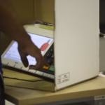 Pessoa utilizando uma urna eletrônica durante votação.