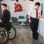 Um funcionário em uma cadeira de rodas trabalha no balcão de uma cafeteria ao lado de outro funcionário com síndrome de down.