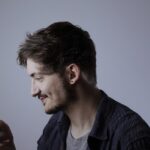 Pessoa segura e observa a tela de um celular. A imagem ilustra o uso de biometria facial e tecnologias de reconhecimento de identidade por pessoas com deficiência.
