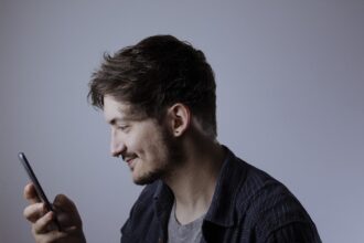 Pessoa segura e observa a tela de um celular. A imagem ilustra o uso de biometria facial e tecnologias de reconhecimento de identidade por pessoas com deficiência.