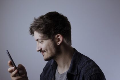 Pessoa segura e observa a tela de um celular. A imagem ilustra o uso de biometria facial e tecnologias de reconhecimento de identidade por pessoas com deficiência.