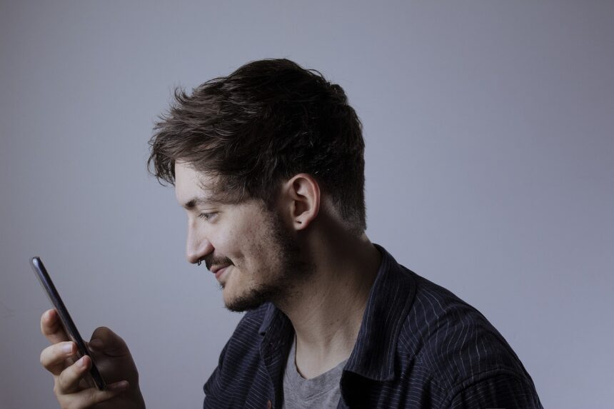 Pessoa segura e observa a tela de um celular. A imagem ilustra o uso de biometria facial e tecnologias de reconhecimento de identidade por pessoas com deficiência.